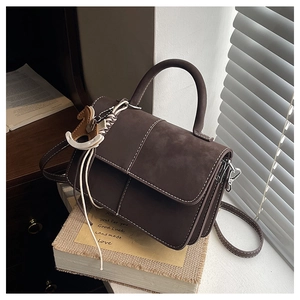 Close-up of brown vintage crossbody bag with white stitching and horse charm