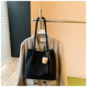 Detail of black suede tote bag featuring a cute bear pendant and stylish fringe decor
