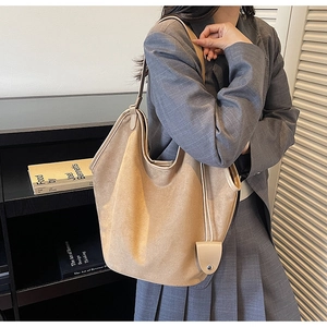 Détail d'un grand sac bandoulière en daim marron avec petite breloque pour les déplacements