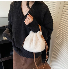 Detailed view of plush white faux fur bucket bag with brown drawstring on model outfits