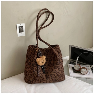 Close-up of leopard print tote bag with brown plush bear charm in a lifestyle setting