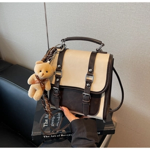 Detail of vintage beige and brown crossbody bag with silver studs and bear charm