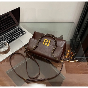 Close-up of retro dark brown square bag with gold metal logo and beaded tassel