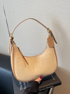 Leopard print crescent moon bag in khaki with adjustable leather strap on books
