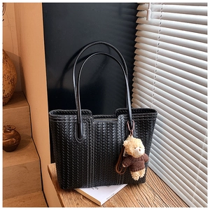 Detail of woven texture on black tote bag with cute bear charm in window light