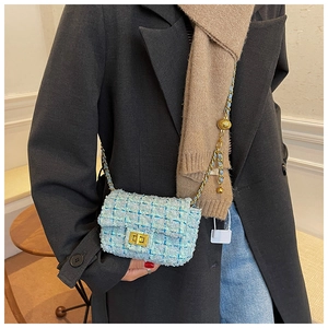 Detail of tweed crossbody bag featuring a golden rotary lock and chain with a ball adjuster