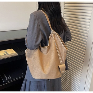 Détail montrant la texture mate et la bandoulière d'un grand sac cabas en daim camel