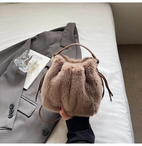 Detail showing plush brown bucket bag with drawstring closure and leather handle