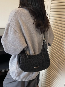 Chic black leopard print crescent moon bag worn by a model in a minimal setting