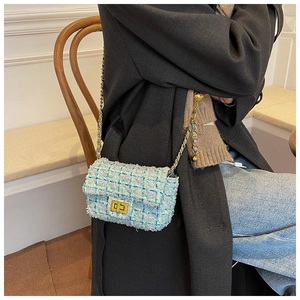 Detailed view of women's tweed crossbody bag with gold chain and elegant metal twist lock