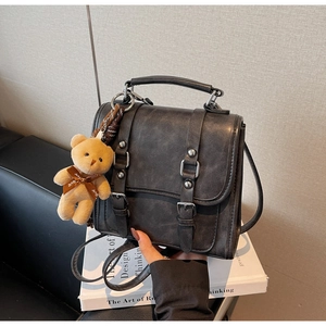 Detailed view of dark grey vintage backpack with retro buckles and cute bear charm