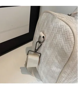 Détail du crochet métallique et texture tissée en chevrons du sac de voyage