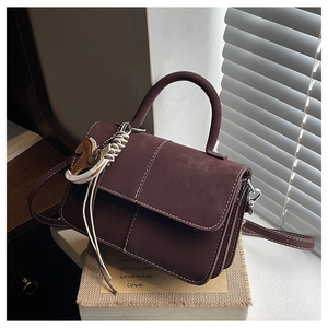 Detail of burgundy matte leather square bag with white stitching and pony charm