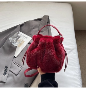 Close-up of plush burgundy faux fur bucket bag with drawstring and leather handles