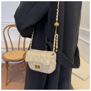 Close-up of elegant white tweed crossbody bag with gold chain strap and adjustable ball