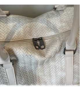 Gros plan détaillé des doubles fermetures éclair en métal sur un sac de voyage tissé
