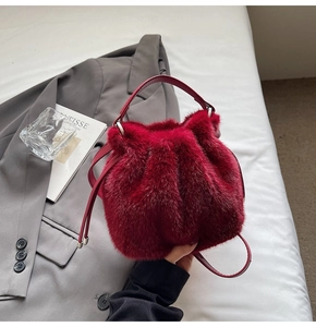 Detail of burgundy plush bucket bag featuring soft faux fur, drawstring and leather handle