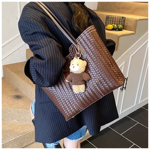 Detail of dark brown woven tote bag with a cute teddy bear charm in retro British style
