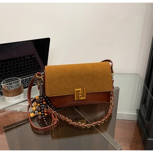 Detail of retro brown suede handbag with golden geometric clasp and chain strap