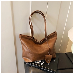 Detail of vintage dark brown faux leather tote bag with heart charm on a black book