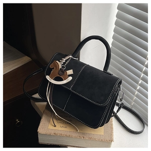 Detail of black crossbody bag with white contrast stitching and wooden horse charm