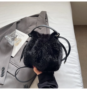Detailed view of plush black faux fur bucket bag with smooth leather drawstring details