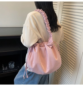 Detail der rosa Cord-Schultertasche mit plissiertem Trageriemen und Kordelzugverschluss