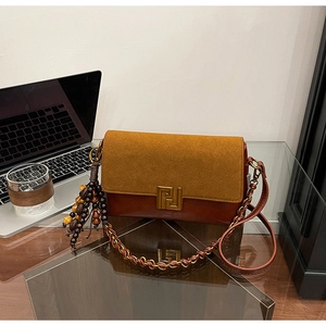 Detail of two-tone chain bag with yellow suede flap and vintage geometric metal clasp