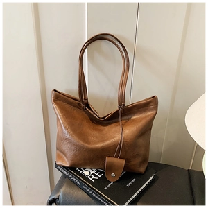Macro detail of brown leather tote bag texture and slim straps on design books