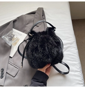 Close-up of black faux fur bucket bag with leather drawstring and textured handle detail
