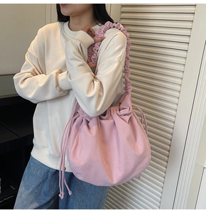 Detail der rosa Cord-Beuteltasche mit gerafftem Riemen, an einem Model im Innenraum