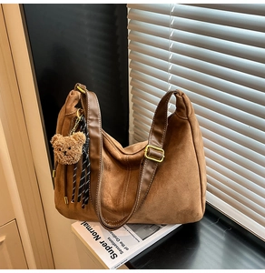 Dettaglio della borsa tote in pelle scamosciata marrone con tracolla e ciondolo a orso