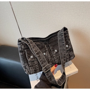 Détail du sac bandoulière en denim gris avec deux poches avant et boucles en métal argenté