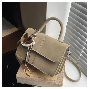 Detail of beige leather crossbody bag with a horse charm on decorative background