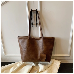 Detail of vintage dark brown tote bag showing litchi grain texture and small pouch