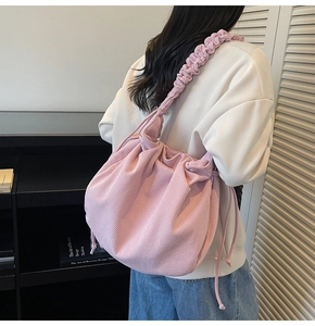 Detailansicht der rosa Cord-Tasche mit gewebtem Schultergurt und weicher Faltenstruktur
