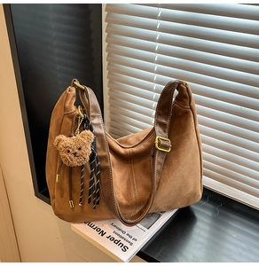 Dettaglio borsa tote in pelle scamosciata marrone con orsetto e fibbia dorata