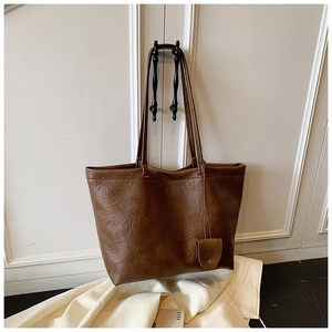 Detail of dark brown tote bag with wrinkled texture and matching mini pouch accessory