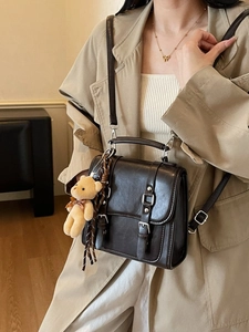 Deep brown vintage messenger bag with double buckles and a plush bear pendant