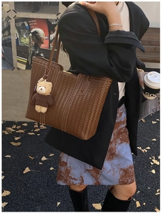 Close-up of brown woven leather tote bag texture with cute teddy bear charm