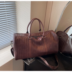 Vue détaillée du sac de voyage marron foncé tissé avec bandoulière et doubles anses