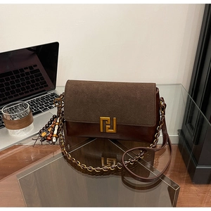 Detail of vintage bicolor crossbody bag featuring brown suede and gold geometric clasp
