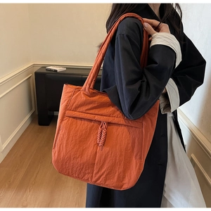 Detail der orangefarbenen gesteppten Tragetasche mit geflochtenem Knoten und Tasche