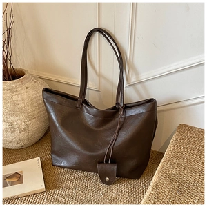 Close-up of a large dark brown leather tote bag with fine textures and elegant shoulder straps