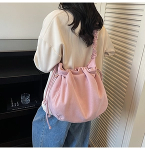 Detail der rosa Cord-Schultertasche mit gerafftem Riemen und Kordelzug am Modell