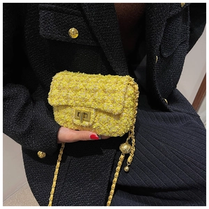 Detailed close-up of yellow tweed texture and golden metal ball charm on a mini chain bag