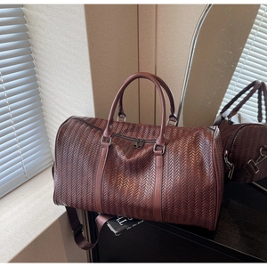 Détails de sac de voyage marron avec texture tressée à chevrons et poignées robustes