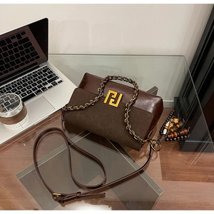 Detail of vintage brown leather bag showing gold logo and beaded fringe tassel