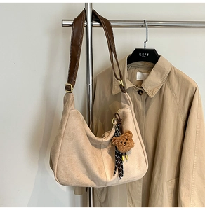 Dettaglio della borsa tote in pelle scamosciata beige con tracolla e ciondolo a orso