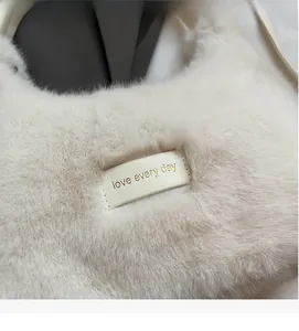 Close-up of fluffy cream plush bag featuring a leather patch with love every day text